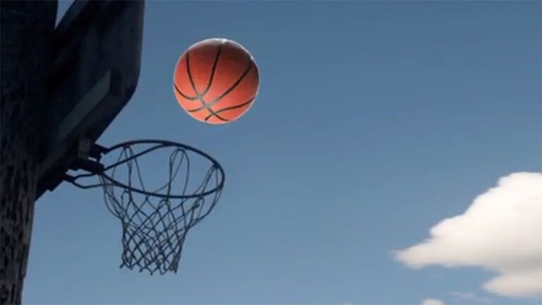 A basketball in midflight approaches the hoop and backboard
