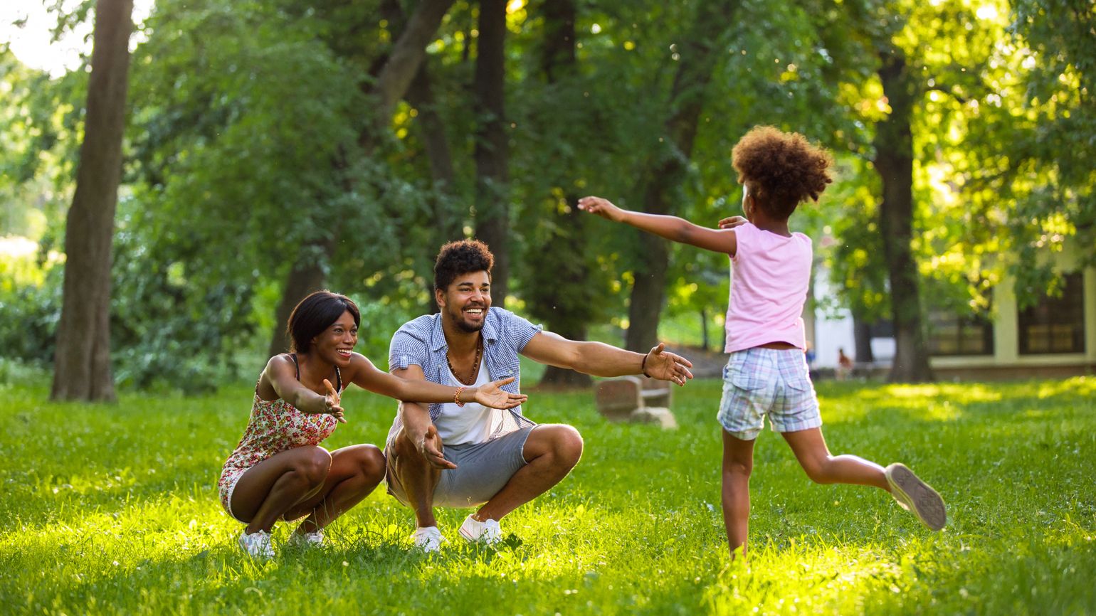 A young girl having fun in the park with her parents.
