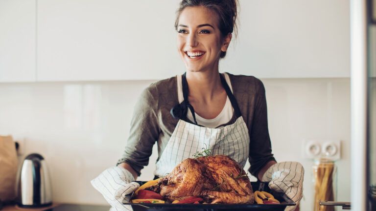 Smiling woman holding a tray of Thanksgiving turkey.