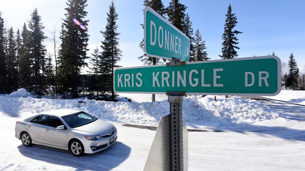 A car in snow at the intersection of Kris Kringle and Donner street signs