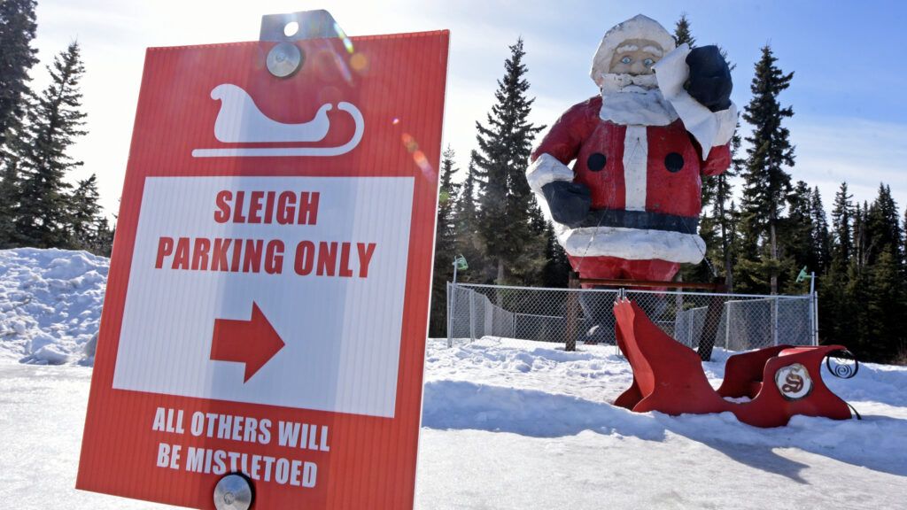 A funny parking sign with the Santa statue in the background